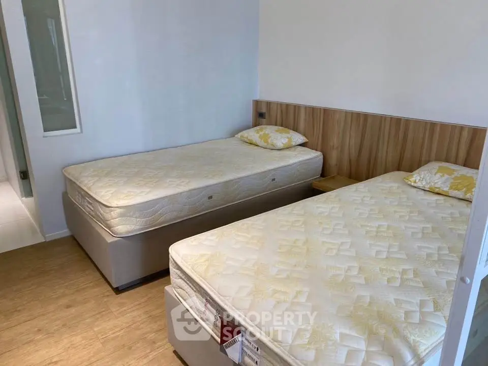 Modern bedroom with twin beds and wooden flooring, perfect for a cozy living space.