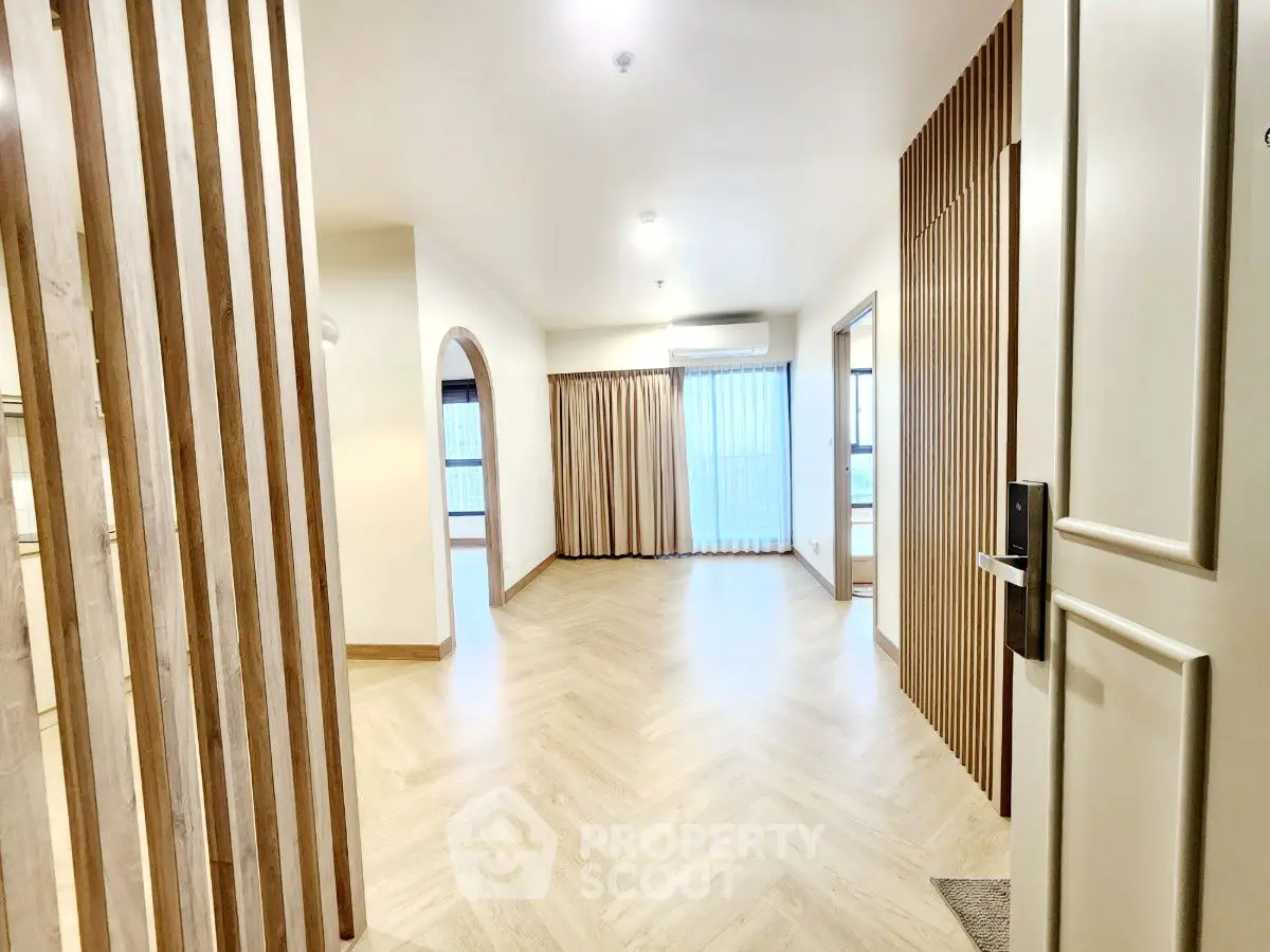 Spacious modern living room with wooden accents and large windows for natural light.