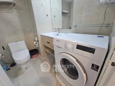 Modern bathroom with washing machine and sleek fixtures in a contemporary apartment.