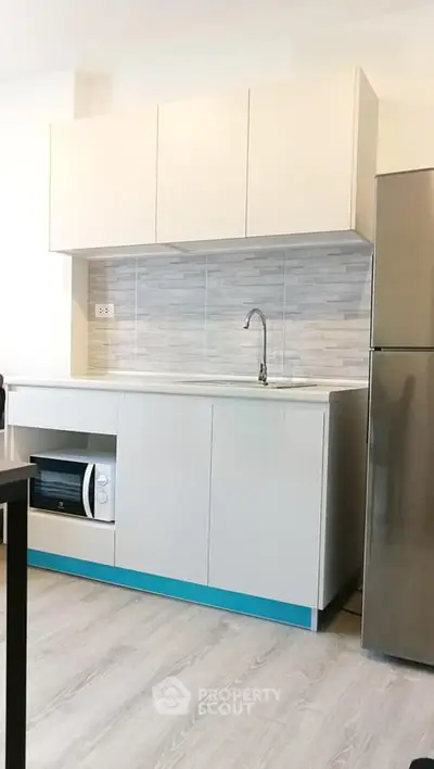 Modern kitchen with sleek cabinetry and stainless steel fridge in a stylish apartment.