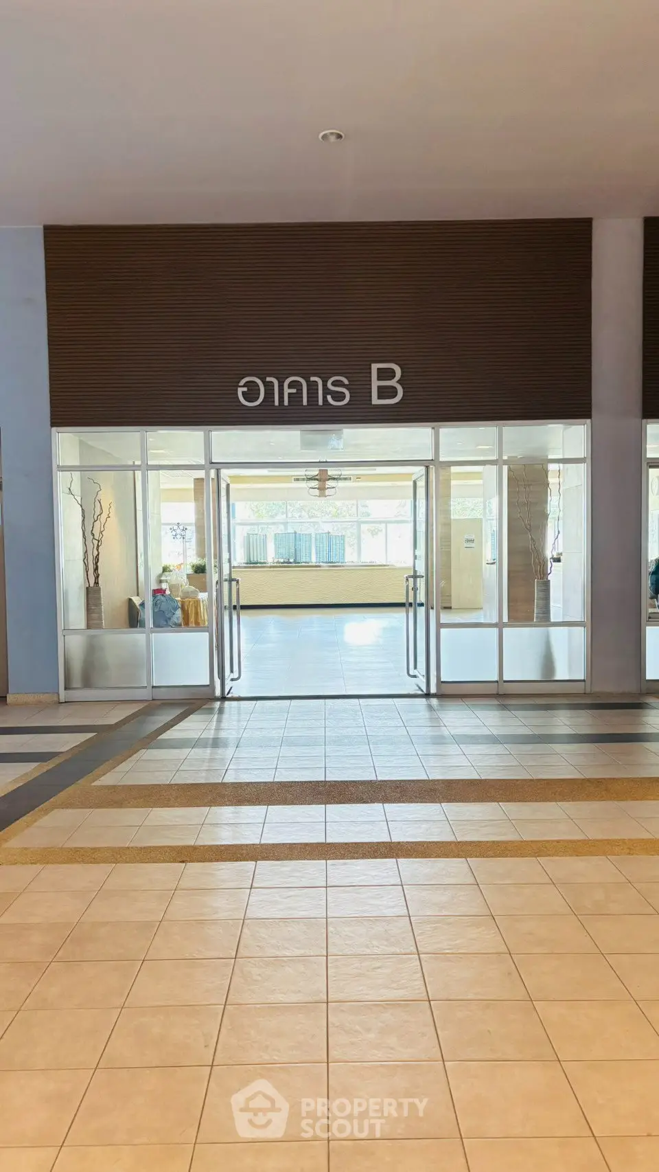 Spacious building entrance with glass doors and tiled flooring in a modern complex.