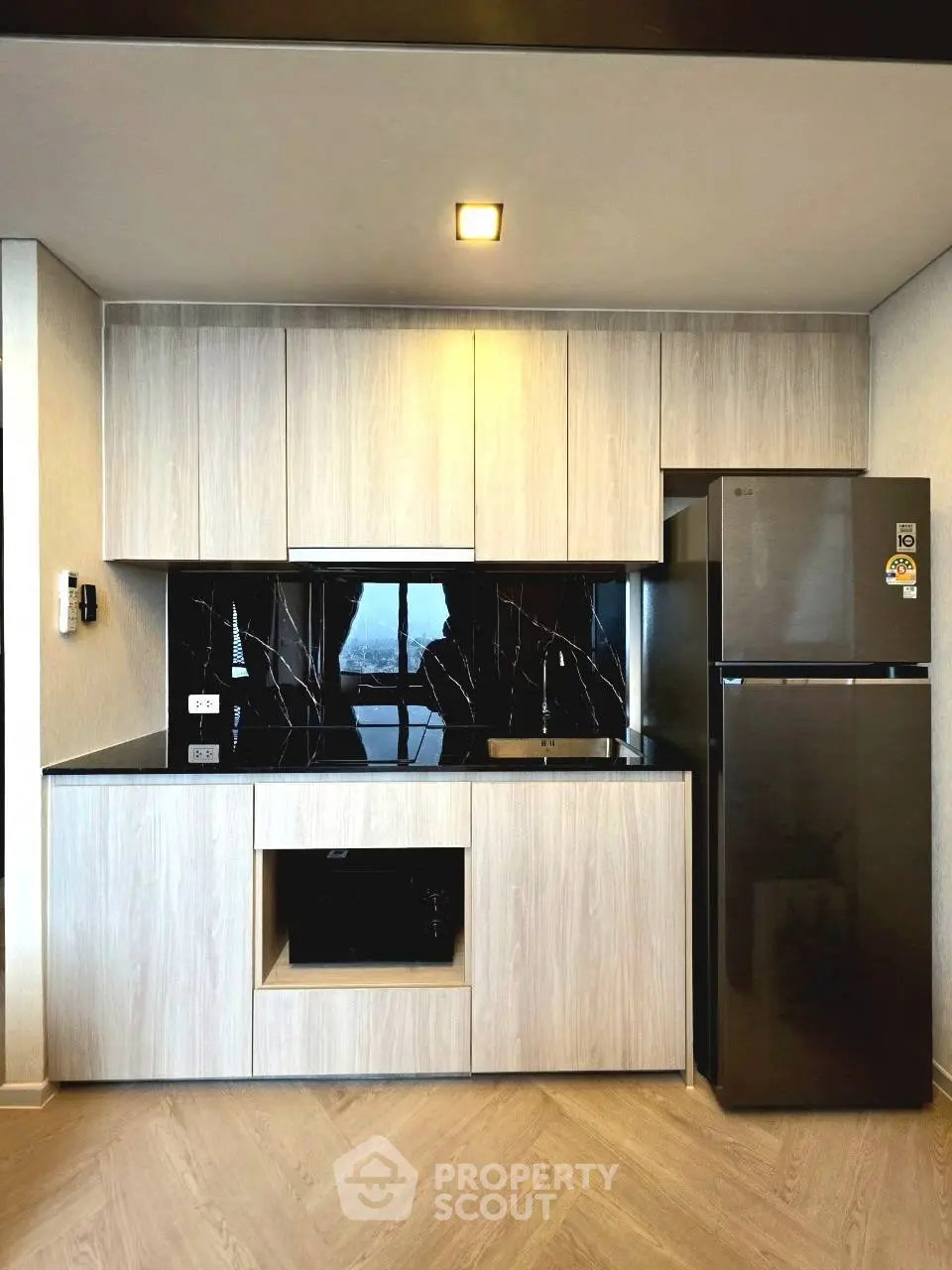 Modern kitchen with sleek cabinetry and stainless steel fridge in a contemporary apartment.