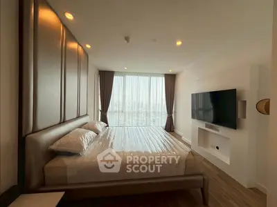 Luxurious bedroom with city view, modern decor, and large TV setup.
