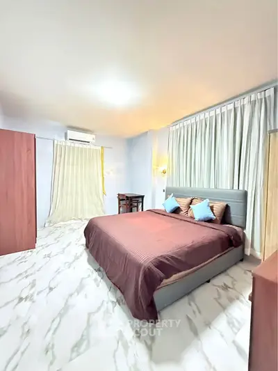 Spacious bedroom with modern decor and ample natural light, featuring a comfortable bed and stylish furnishings.