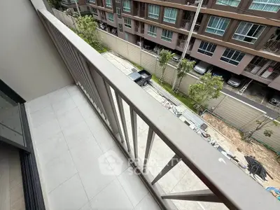 Modern apartment balcony with view of residential complex and street below.