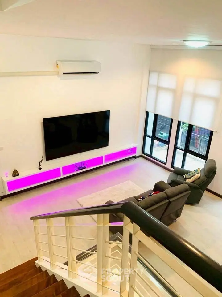 Modern living room with stylish lighting and large TV, featuring cozy seating and elegant decor.