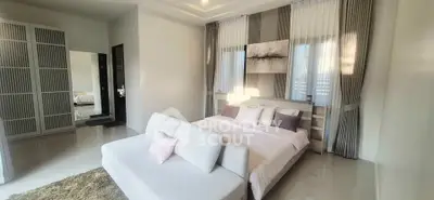 Luxurious bedroom with elegant decor and natural light, featuring a cozy seating area and modern design.