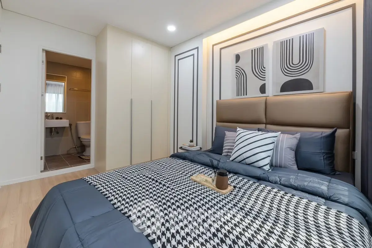 Modern bedroom with stylish decor and ensuite bathroom in a contemporary apartment.