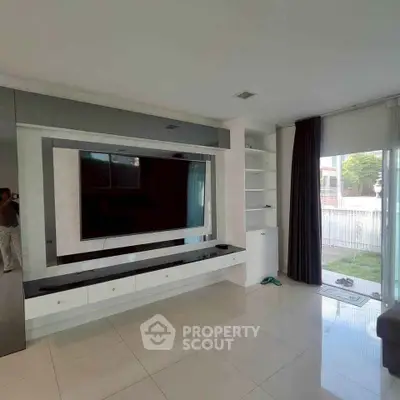 Modern living room with sleek TV unit and large windows offering natural light.