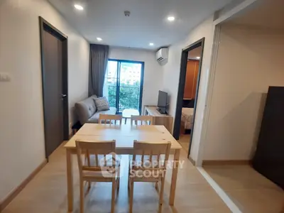 Modern apartment interior with open living and dining area, featuring a cozy sofa and large window view.