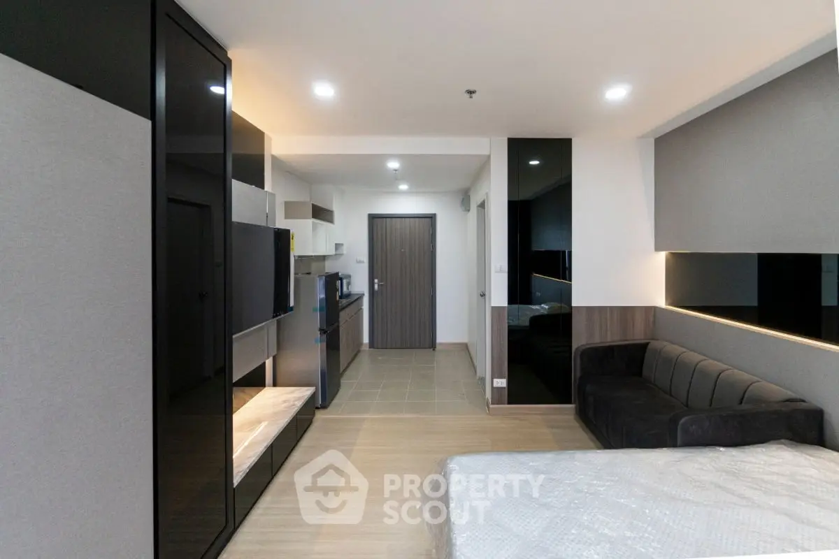 Modern studio apartment with sleek design, featuring a cozy living area and compact kitchen.