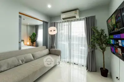 Modern living room with sleek sofa, wall-mounted TV, and large window for natural light.