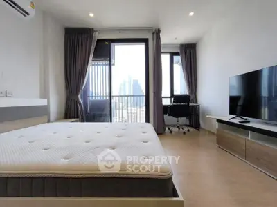 Modern bedroom with city view, featuring a large bed, TV, and workspace, ideal for urban living.