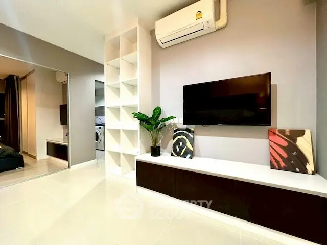 Modern living room with sleek TV setup and air conditioning, featuring stylish decor and ample storage.