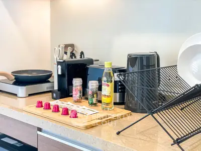 Modern kitchen counter with appliances and coffee capsules, showcasing sleek design and functionality.
