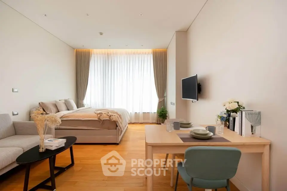 Modern studio apartment with cozy bedroom and stylish living area, featuring elegant decor and natural light.