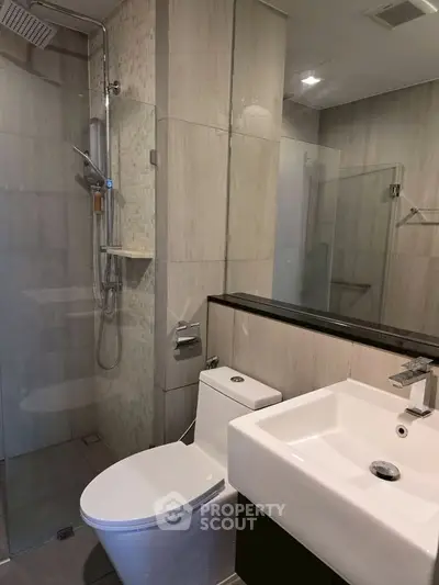 Modern bathroom with sleek fixtures and glass shower enclosure in a contemporary apartment.