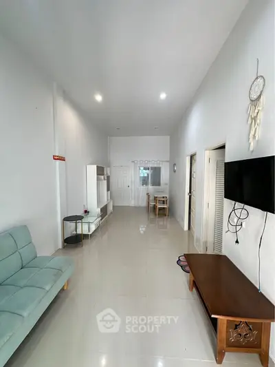 Spacious living room with modern decor and high ceilings, featuring a comfortable sofa and wall-mounted TV.