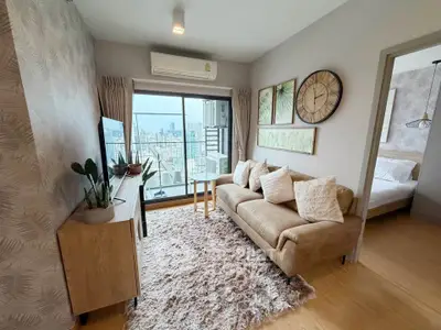 Modern living room with city view, cozy sofa, and stylish decor in a high-rise apartment.