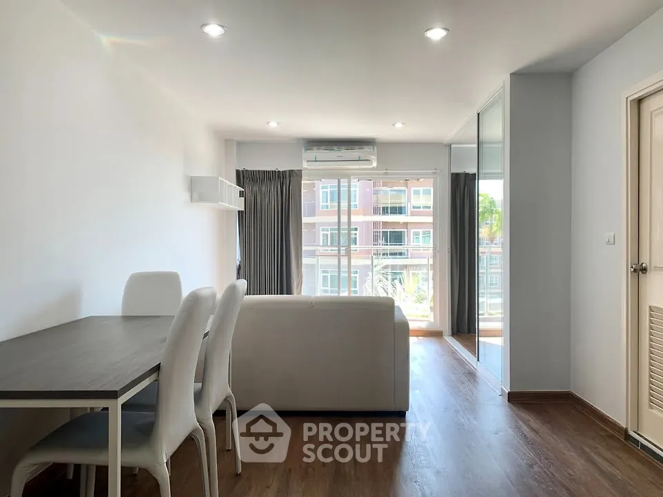 Modern living room with dining area and large windows in a bright apartment.