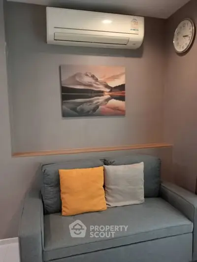 Cozy living room with modern sofa, wall art, and air conditioning unit.