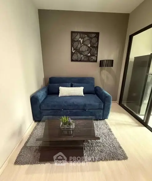 Cozy living room with blue sofa, modern decor, and glass coffee table on a plush rug.