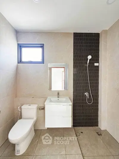 Modern bathroom with sleek design featuring a shower, toilet, and vanity in neutral tones.