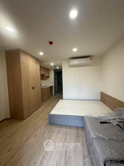 Modern bedroom with wooden flooring, built-in wardrobe, and air conditioning unit.