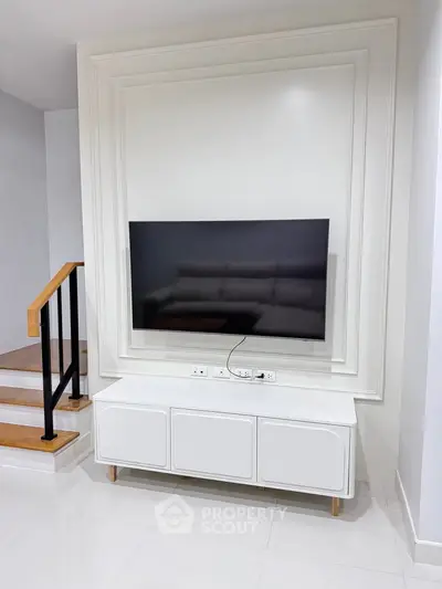 Modern living room with sleek TV setup and stylish staircase