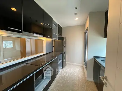 Modern kitchen with sleek black cabinetry and stainless steel appliances in a stylish apartment.
