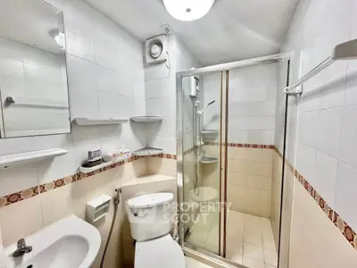 Compact bathroom with shower, toilet, and sink in a modern apartment.