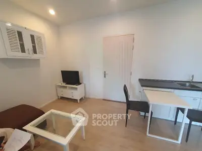 Modern living room with minimalist furniture and integrated kitchenette in a cozy apartment.
