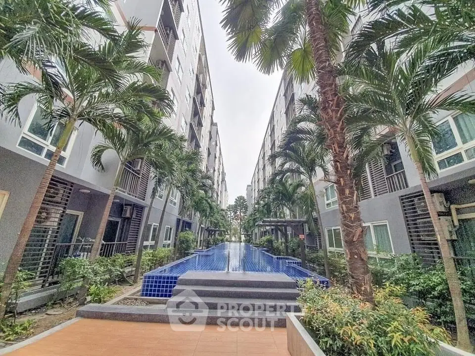 Modern apartment complex with lush landscaping and central pool area.