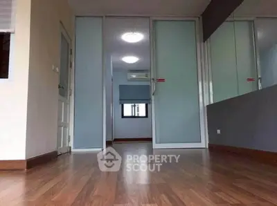 Spacious modern room with wooden flooring and frosted glass doors