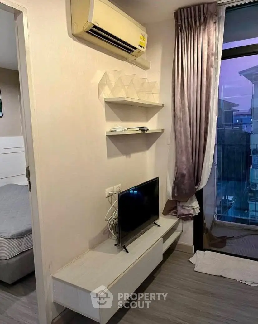 Cozy bedroom corner with TV, air conditioning, and balcony view