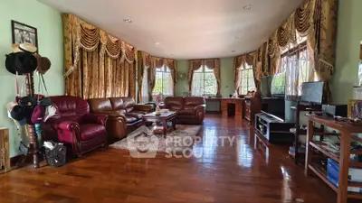 Spacious living room with elegant curtains and leather sofas, perfect for family gatherings.