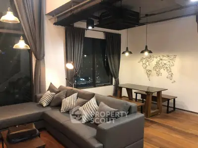 Modern living room with stylish decor and city view, featuring a comfortable gray sofa and elegant lighting.