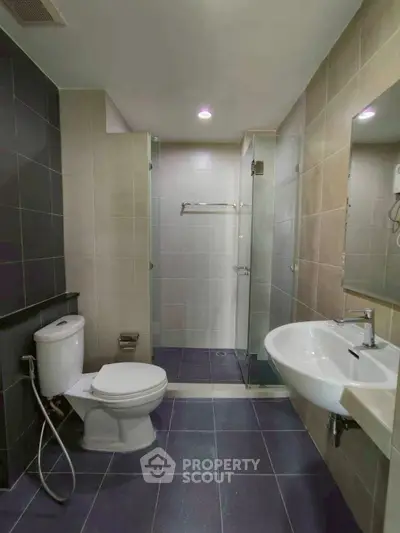 Modern bathroom with sleek fixtures and glass shower enclosure in a contemporary apartment.