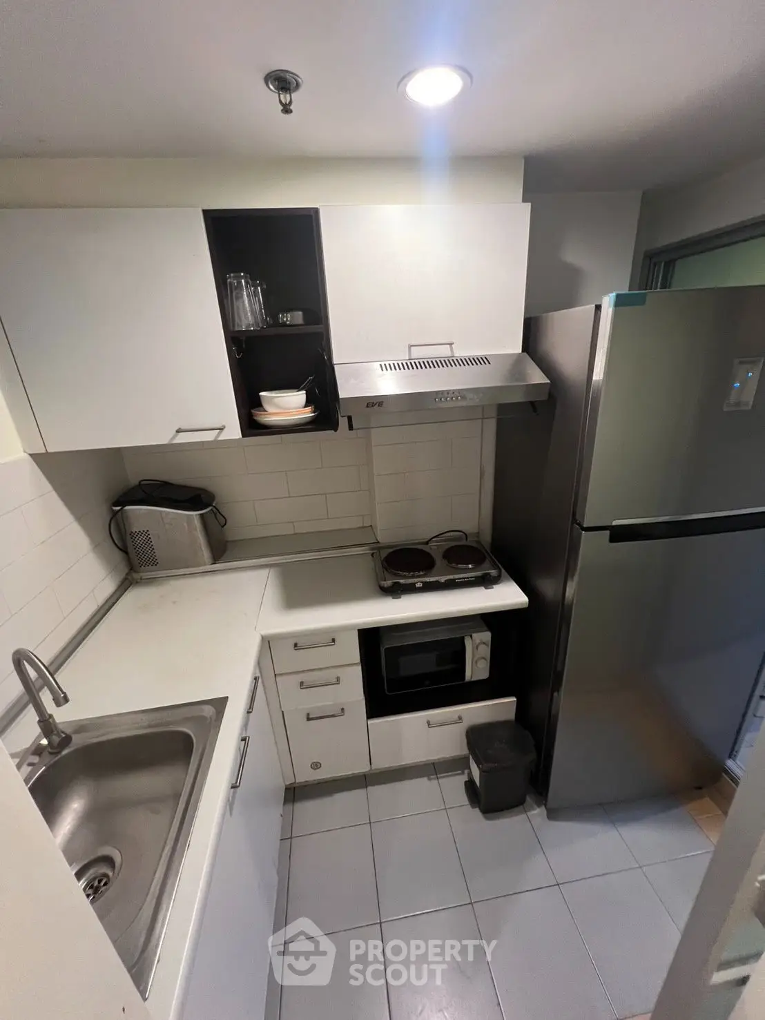 Compact kitchen with modern appliances and sleek white cabinetry
