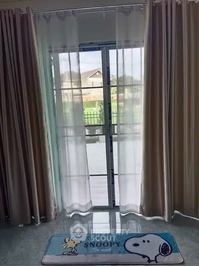 Charming interior view with elegant curtains and Snoopy-themed mat by a glass door.