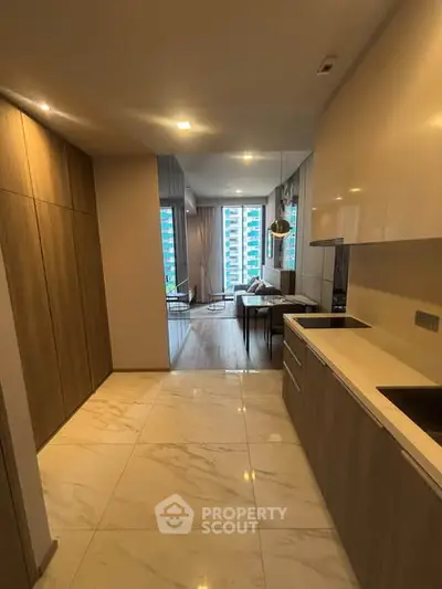 Modern open-layout kitchen with sleek cabinetry and marble flooring leading to a bright living area.