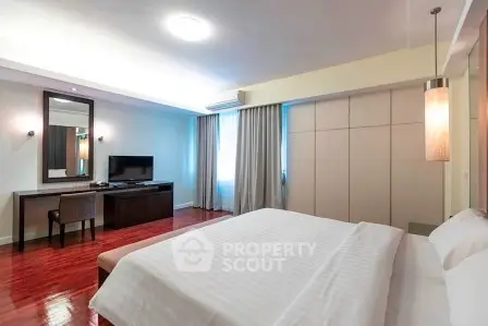 Spacious bedroom with modern decor, featuring a large bed, wooden flooring, and a stylish desk area.