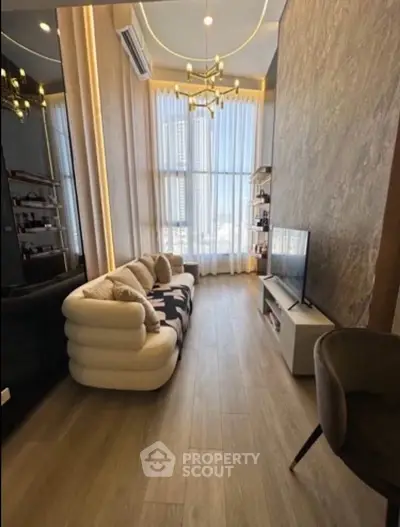 Luxurious living room with high ceilings, elegant chandelier, and large windows offering stunning city views.