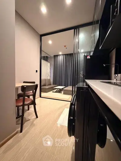 Modern open-layout kitchen leading to a stylish living room with sleek furniture and ambient lighting.