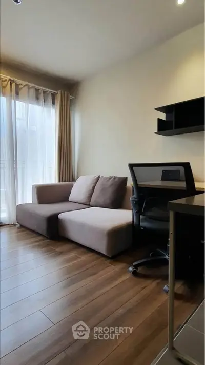 Modern living room with cozy sofa and workspace, featuring wooden flooring and natural light.