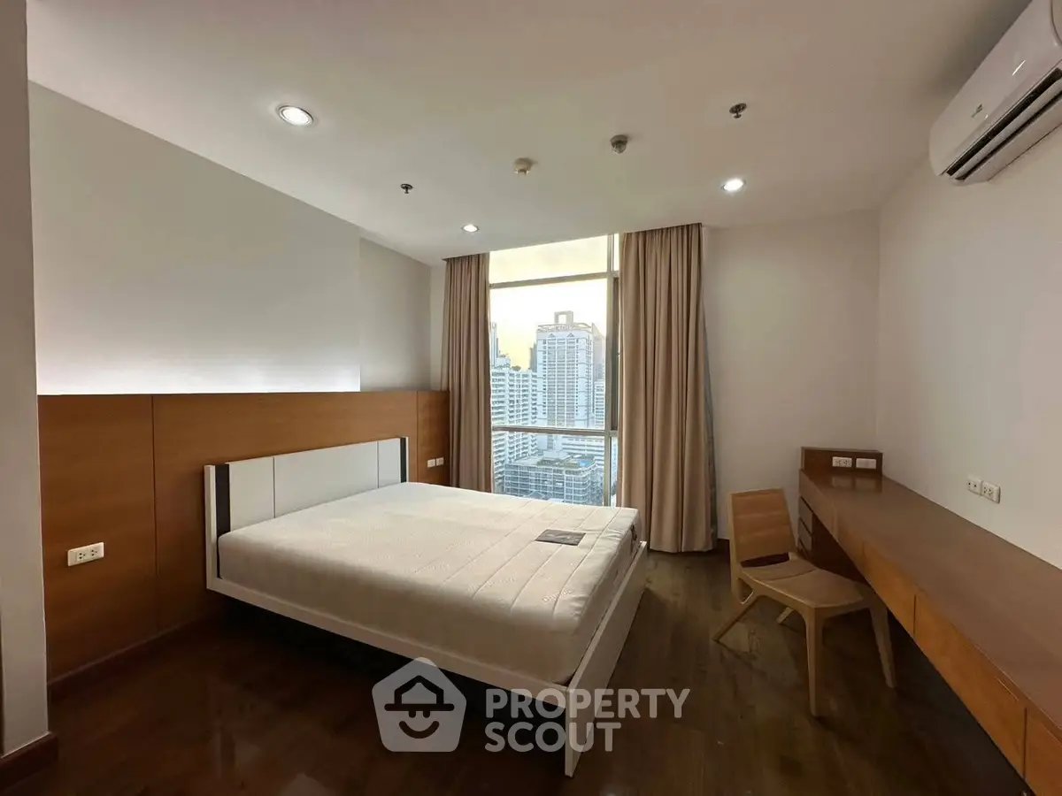 Modern bedroom with city view, featuring sleek wooden furniture and large window for natural light.