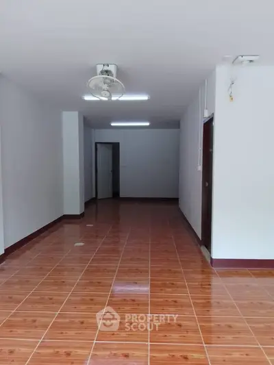 Spacious empty room with polished wooden floor and ceiling fan, ideal for customization.