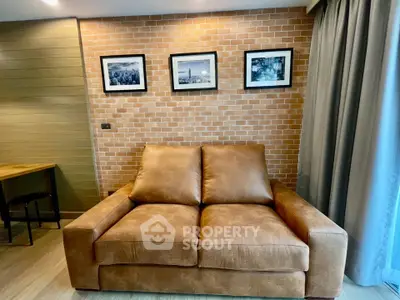 Stylish living room with leather sofa and brick accent wall, perfect for modern urban living.