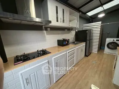 Modern kitchen with gas stove, sleek cabinetry, and washing machine in a stylish open layout.