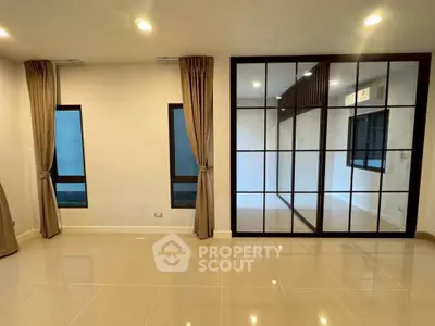 Spacious modern living room with elegant floor-to-ceiling windows and sleek tile flooring.